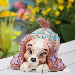 ¡Descubre la encantadora Mini Lady! Esta pequeña figurina, diseñada por el galardonado artista Jim Shore, presenta a Lady, la querida perrita de "La Dama y el Vagabundo". Su postura refleja toda su vivacidad y espíritu juguetón